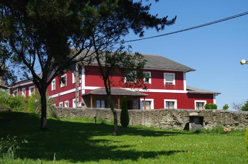 una casa roja con una pared de piedra delante de ella en Hotel Rural Suquin en Navia