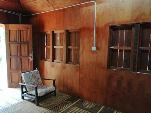 a chair in a room with a wooden wall at Long Titi Homestay in Sematan