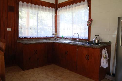 a kitchen with a sink and a large window at Cabañas Pun May in Villarrica