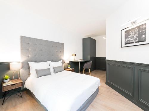 une chambre avec un grand lit blanc et un bureau dans l'établissement LivinParis - Luxury 3 Bedrooms République I, à Paris