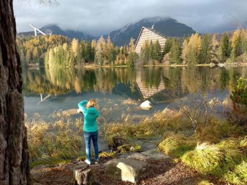 a young girl standing next to a lake at Apartmán Crocus 313 in Štrbské Pleso