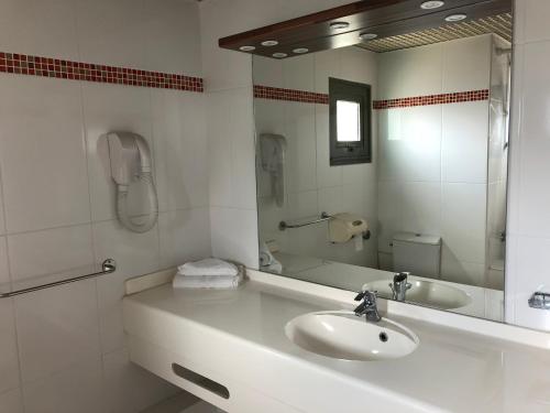 Baño blanco con lavabo y espejo en Hotel La Galleria en Le Lamentin