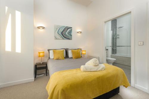 ニューカッスル・アポン・タインにあるCentral Lofts Apartmentのベッドルーム1室(黄色い毛布付きのベッド1台付)