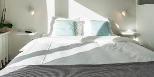 a bed with a white comforter and pillows at Entrenous B&B Ghent in Ghent