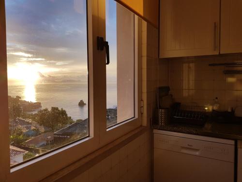 a kitchen window with a view of the ocean at The Sunrise of your Dreams with Total Ocean View in Funchal