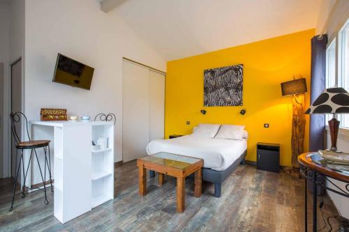 a bedroom with a bed and a table in a room at Villa Mogador Piscine et Balnéo in Andernos-les-Bains