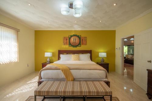 1 dormitorio con 1 cama y reloj en la pared en Tropical Escape Villa, en Ocho Ríos