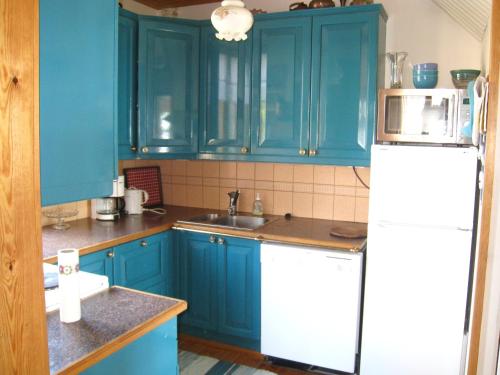 kuchnia z niebieskimi szafkami i białą lodówką w obiekcie Aironiemi Cottage w mieście Kotka