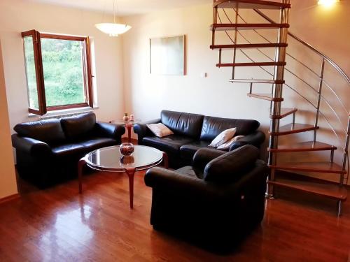 a living room with two leather couches and a spiral staircase at Villa Roses Apartments & Wellness in Ičići