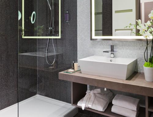 bagno con lavandino e doccia di Hôtel Barrière Ribeauvillé a Ribeauvillé