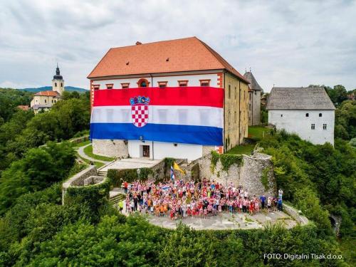 een groep mensen die voor een gebouw met een vlag staan bij Sobe Pavlaković in Ozalj