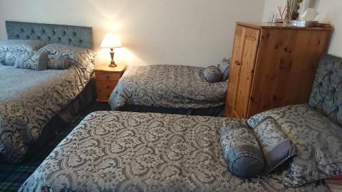 a hotel room with two beds and a dresser at Crawfords Guest house in Peterhead
