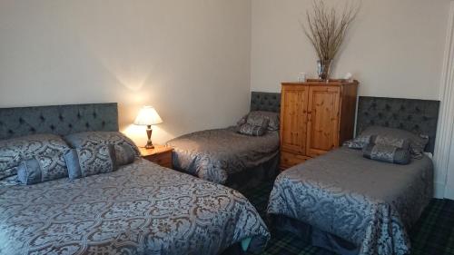 a hotel room with two beds and a dresser at Crawfords Guest house in Peterhead