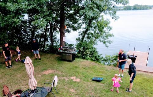 a group of people standing around a grill near the water at Curriers Lakeview Lodge in Rice Lake