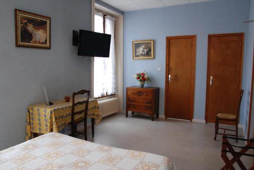 a bedroom with a bed and a table and a television at Hôtel Victoria in Grenoble