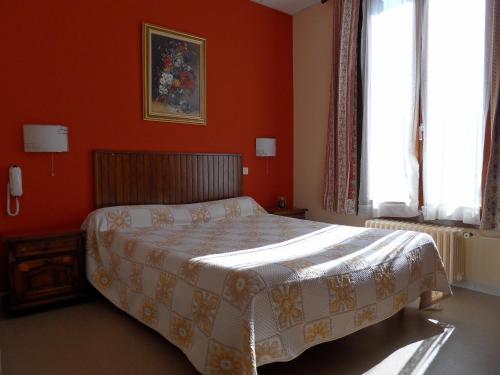 グルノーブルにあるHôtel Victoriaのベッドルーム1室(オレンジ色の壁と窓のあるベッド1台付)