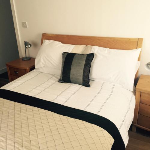 a bed with a black and white comforter and pillows at 6a Cedar Grove in Bangor