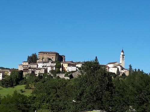 a town on top of a hill with a clock tower at Tolasudolsa Rooms, Breakfast & Mountain Bike in Compiano