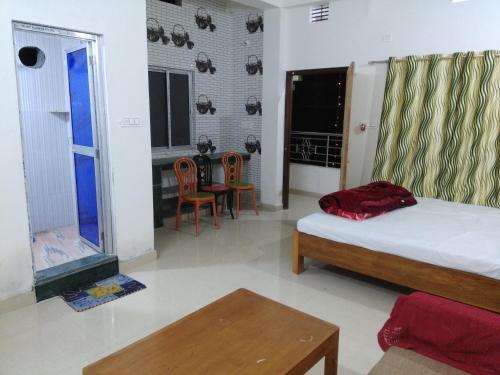 a bedroom with a bed and a table and chairs at Babusona Homestay in Jaldapara in Mādāri Hāt