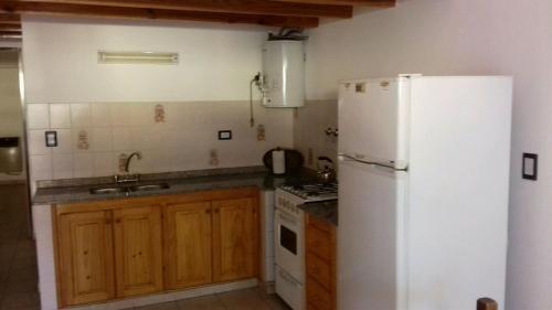 Una cocina con un refrigerador blanco y un fregadero. en Departamentos Silvia, en Santa Teresita