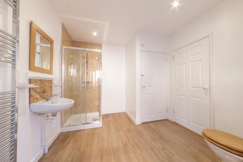 a white bathroom with a shower and a sink at Prince Hill Cottages in Worton