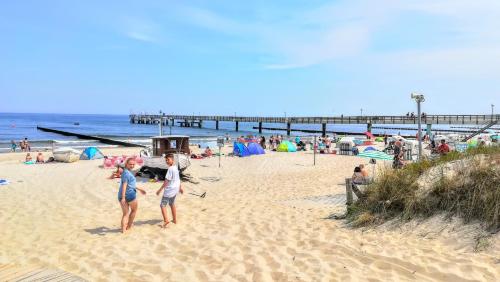 a group of people on a beach with a pier at Koserow Ferienwohnung Fam. Jäger 400m zum Strand in Ostseebad Koserow