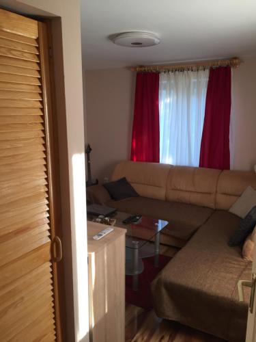 a living room with a couch and red curtains at Izabella Vendégház Somló in Doba