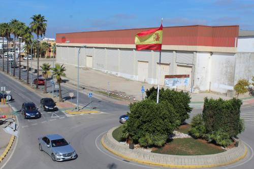 um edifício com uma bandeira e carros numa rua em Pensión Hidalgo 2 em Utrera