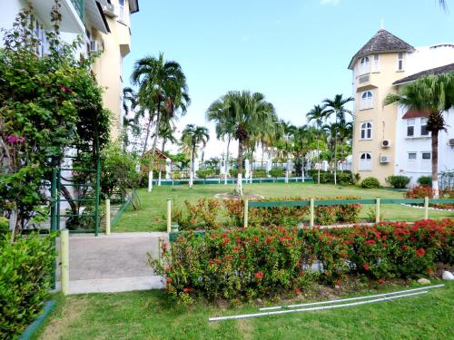a garden in front of a building with palm trees at Beach Studio 10 in Ocho Rios