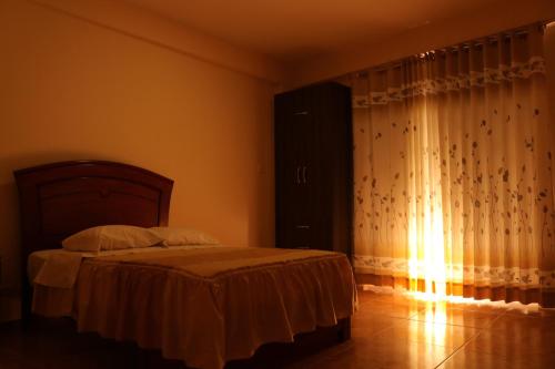 a bedroom with a bed and a window with curtains at hotel el parral suite in Ica