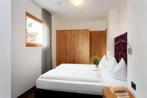 a bedroom with a large white bed and a window at Appartement-Hotel Beatenhof in Tirolo