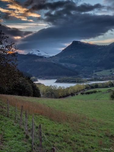 a fence in a field with a mountain and a lake at Casa Rural Urkulu Landetxea in Aretxabaleta