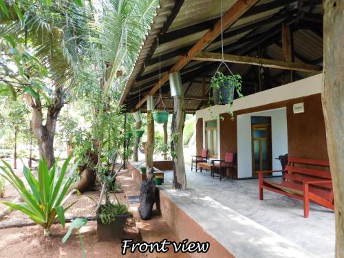 a porch of a house with a bench and trees at Yala Avian Eye Safari in Buttala