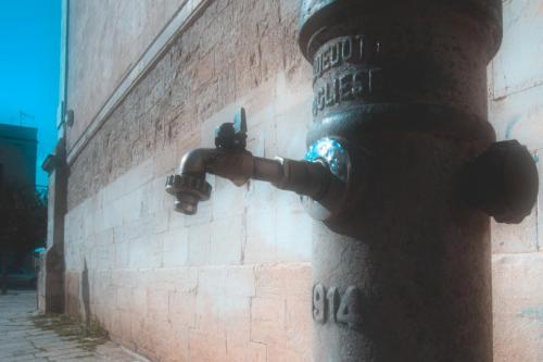 a fire hydrant is attached to a brick wall at Il Vicolo - Affittacamere in Ruvo di Puglia