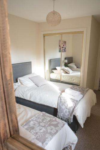 a bedroom with two beds and a mirror at South Groathill - Lovely 2 bed with Castle View in Edinburgh