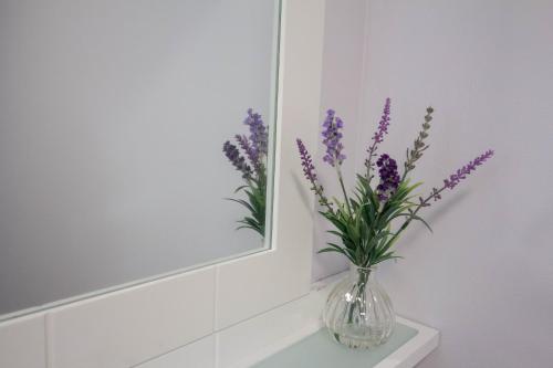 a vase of purple flowers sitting on a shelf in front of a mirror at South Groathill - Lovely 2 bed with Castle View in Edinburgh