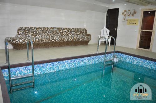 a swimming pool with a couch in a living room at Shaarei Zion in Umanʼ