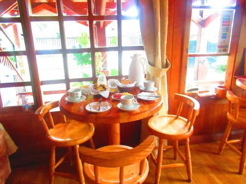 una mesa de madera con tazas y platillos delante de una ventana en Alojamientos La Casita del Centro, en Panguipulli