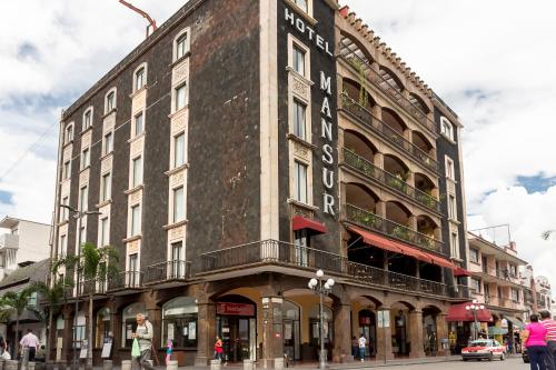 a tall building on a city street with people walking in front at Hotel Mansur Business & Leisure in Córdoba