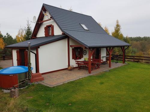 una pequeña casa blanca con una mesa de picnic en el patio en 4 Pory Kaszub - Domek z banią i sauną, en Skoszewo