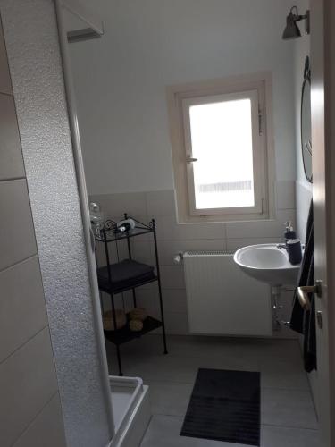 a white bathroom with a sink and a window at Ferienwohnung Frühlingsau in Freudenstadt
