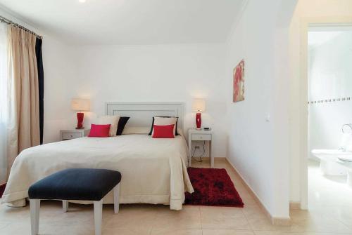 a white bedroom with a large bed with red pillows at Amelie in Carvoeiro