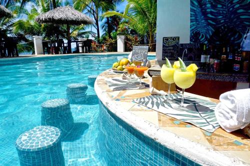 una piscina con bicchieri di bevande su un tavolo di Vista Coiba Villas & Restaurant a Santa Catalina