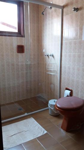 uma casa de banho com uma cabina de duche em vidro e um WC. em Dormitórios Praia da Lagoinha em Ubatuba