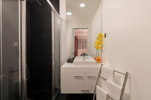 W białej łazience znajduje się umywalka i lustro. w obiekcie VILLA PARADISE - Modern and Sophisticated w Funchal