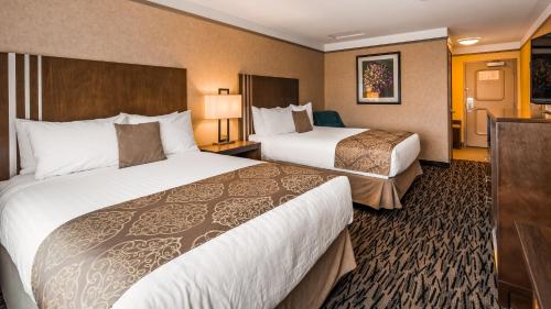 a hotel room with two beds and a television at Best Western Plus Pitt Meadows Inn & Suites in Pitt Meadows