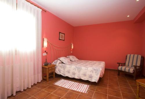 a bedroom with red walls and a bed and a chair at Hotel Rural Suquin in Navia