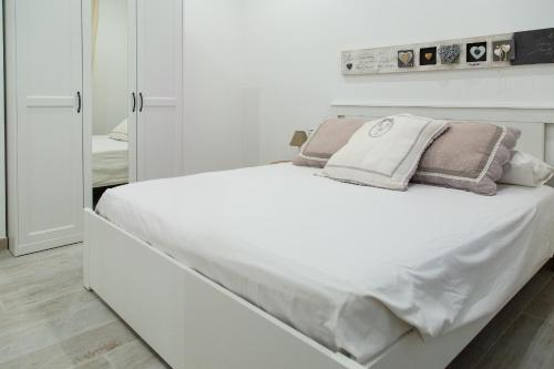 una camera bianca con un grande letto bianco con cuscini di Eur Home a Roma