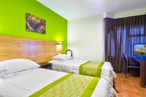 two beds in a hotel room with a green wall at Hotel Residence Inn Suites Cristina in San José
