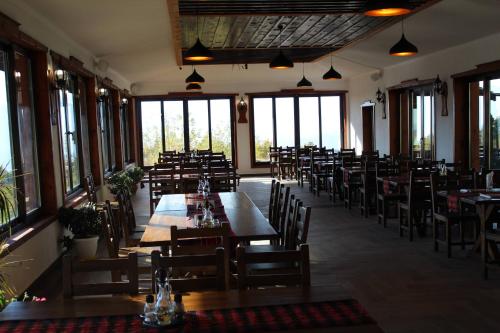 un restaurante con mesas y sillas de madera y ventanas en Leshtenski Perli, en Leshten